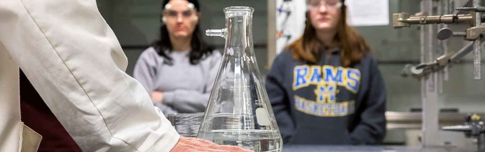 Image of a professor with test tube and students.