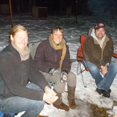 Three students from the Arctic and Northern Studies club gather around a bonfire | UAF Photo