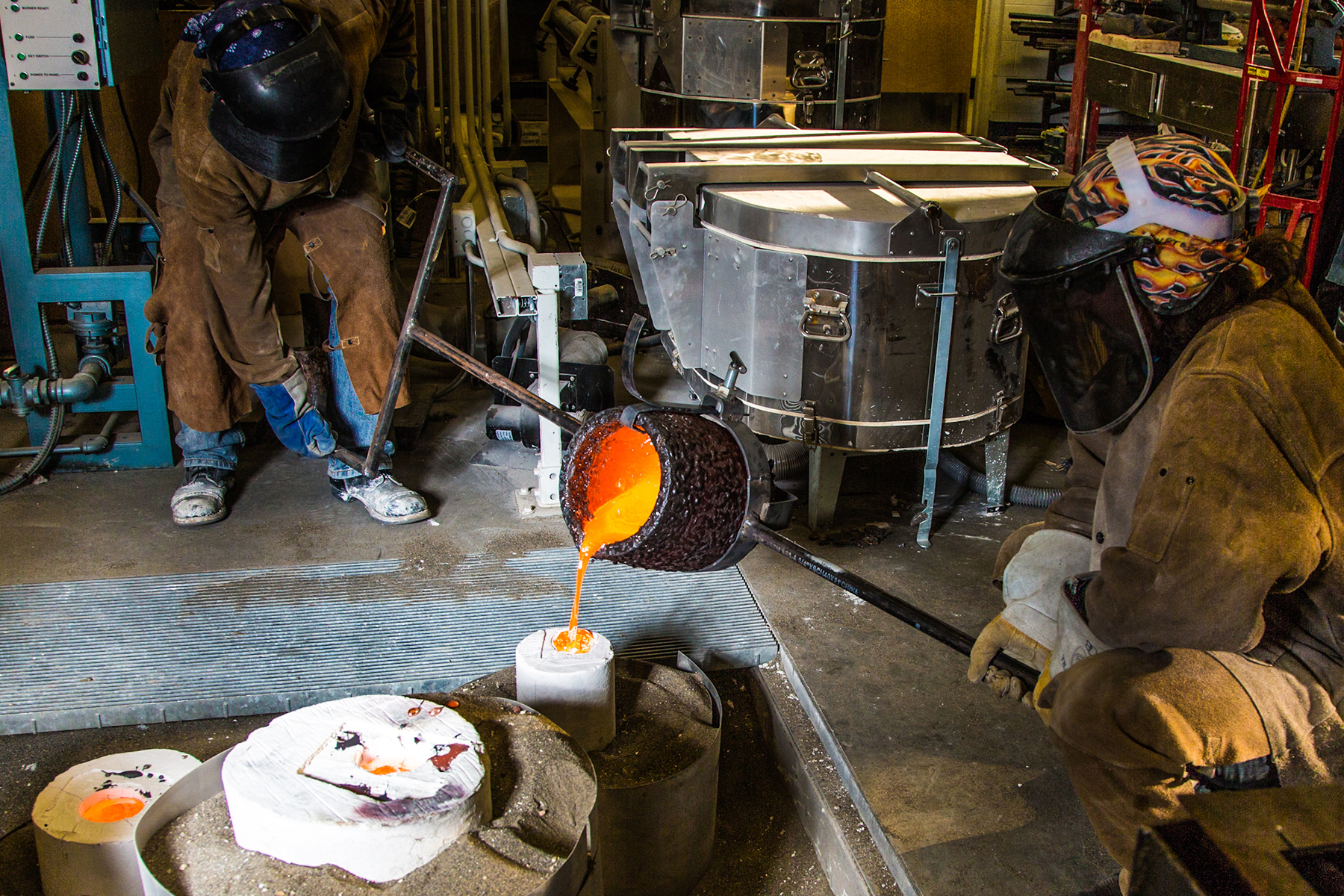 Art major Joel Isaak, left, fills a mold with molten bronze as part of the process of creating a life-sized sculpture for his senior thesis in the UAF Fine Arts complex.