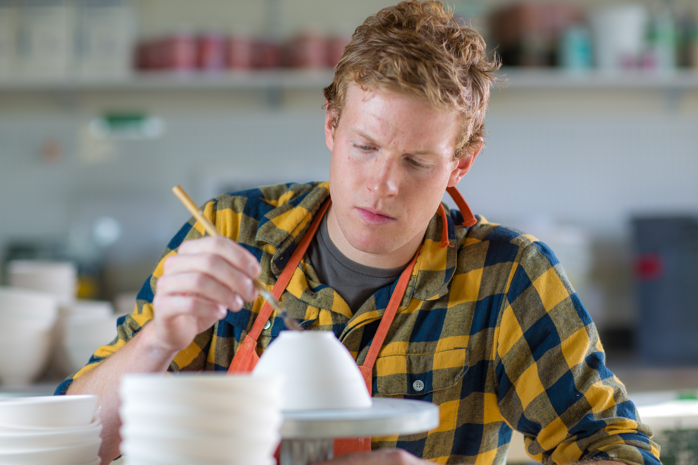 Art major Ian Wilkinson works on one of the approximately 1,000 ceramic bowls needed for his senior thesis project in the fine arts complex on the Fairbanks campus. | UAF Photo by Todd Paris