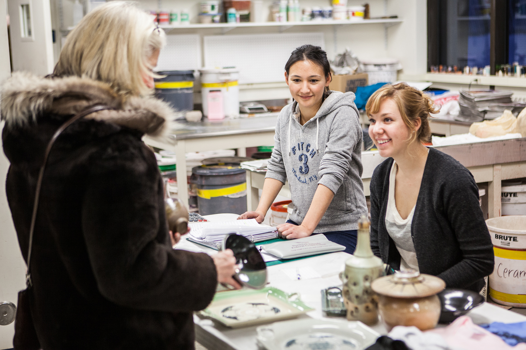 Emily Blurton, center, and Kirsten Olson, complete a transaction during the 2012 Student Artist Ceramics sale in December 2012.
