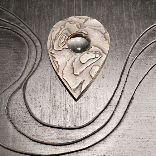 metal topographic planchette by Christen Booth. Image courtesy of the artist