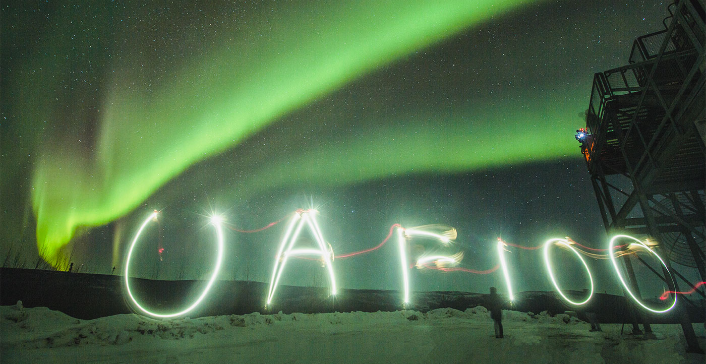 An image of “UAF100,” painted with a cellphone by UAF chief photographer JR Ancheta, is captured by a 30-second exposure under the aurora at the Poker Flat Research Range in February 2017. The figure at bottom right is a researcher awaiting a rocket launch at the range.
