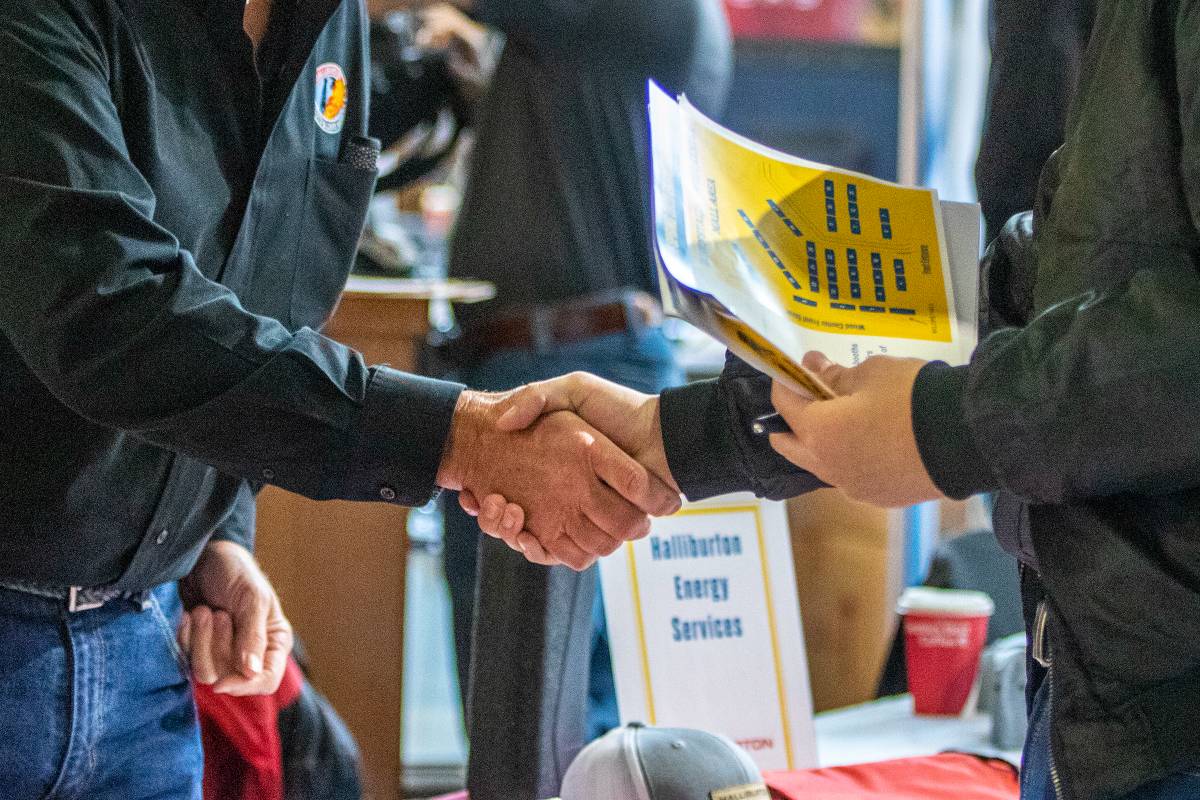 A UAF student and an employer shake hands at a career fair