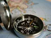 Close-up of a compass sitting on top of a world map.