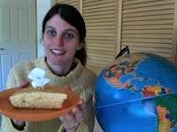 Person holding a plate with a slice of cake, next to a globe.