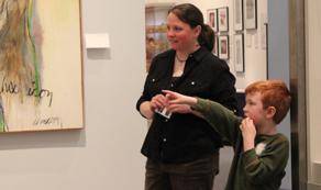 A docent talking to a child. The child is pointing at a painting.