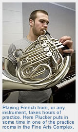 John playing french horn in a practice room in the Fine Arts Complex