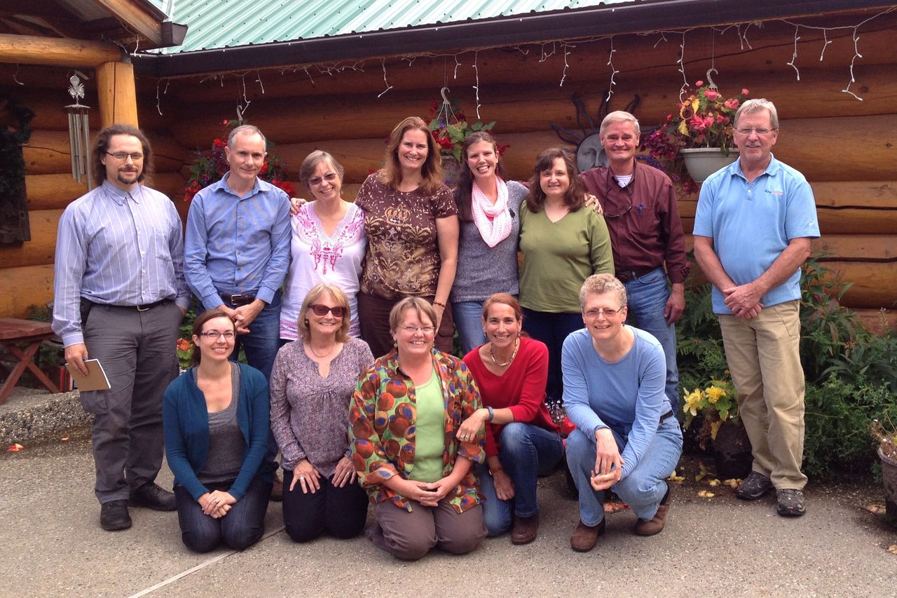 Psychology Faculty in front of log houses