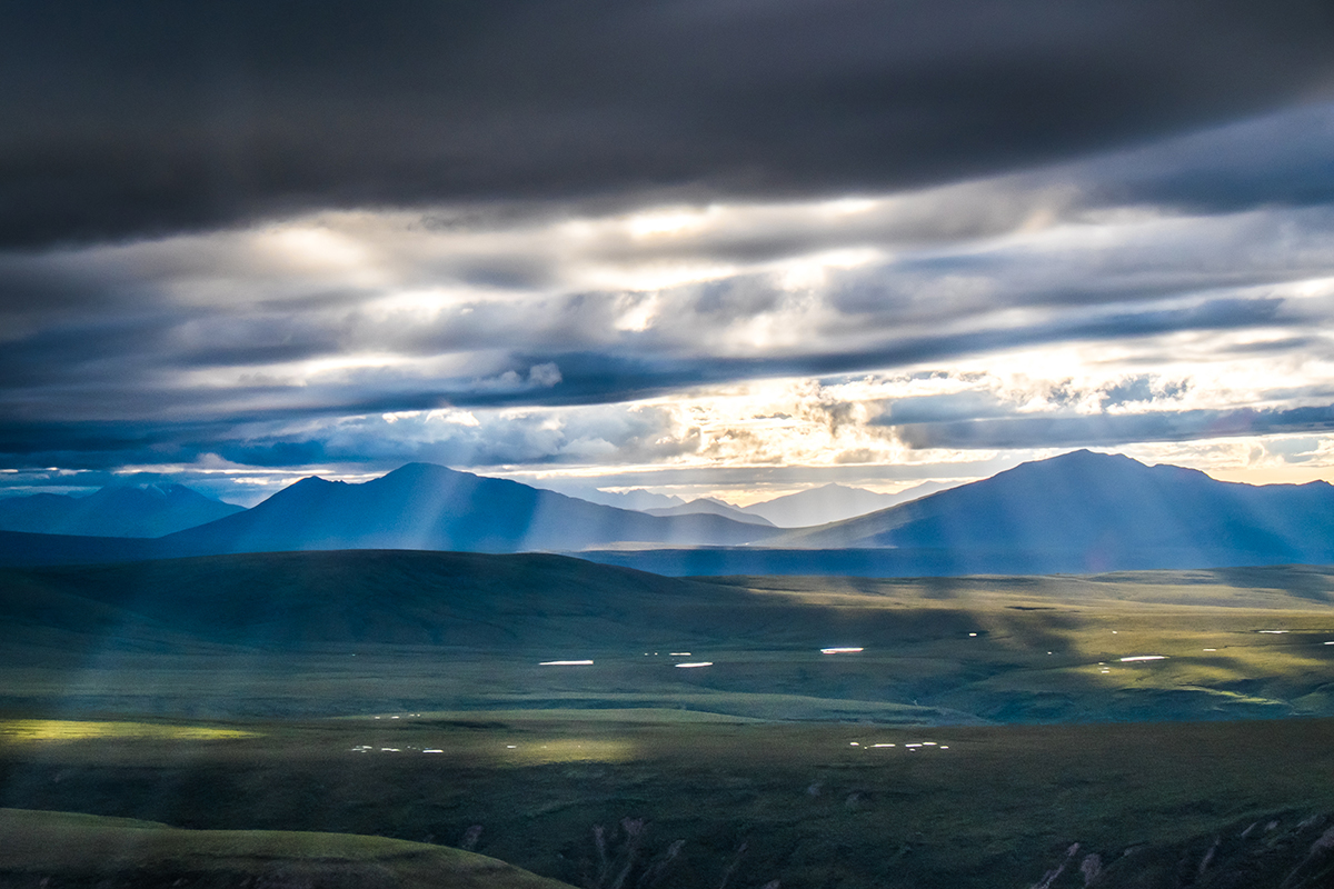 Sunlight filters through the clouds on a July evening in Alaska's eastern Interior.