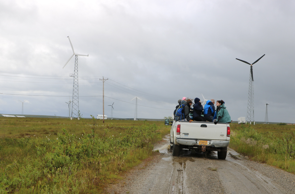 People on a truck and a wind farm