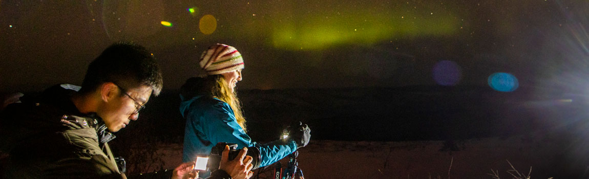 Two students photograph the aurora on a winter night