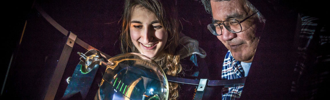 UAF Physics major Haley Nelson and Stanley Edwin experiment with a device that creates an artificial aurora borealis in a Reichardt Building lab