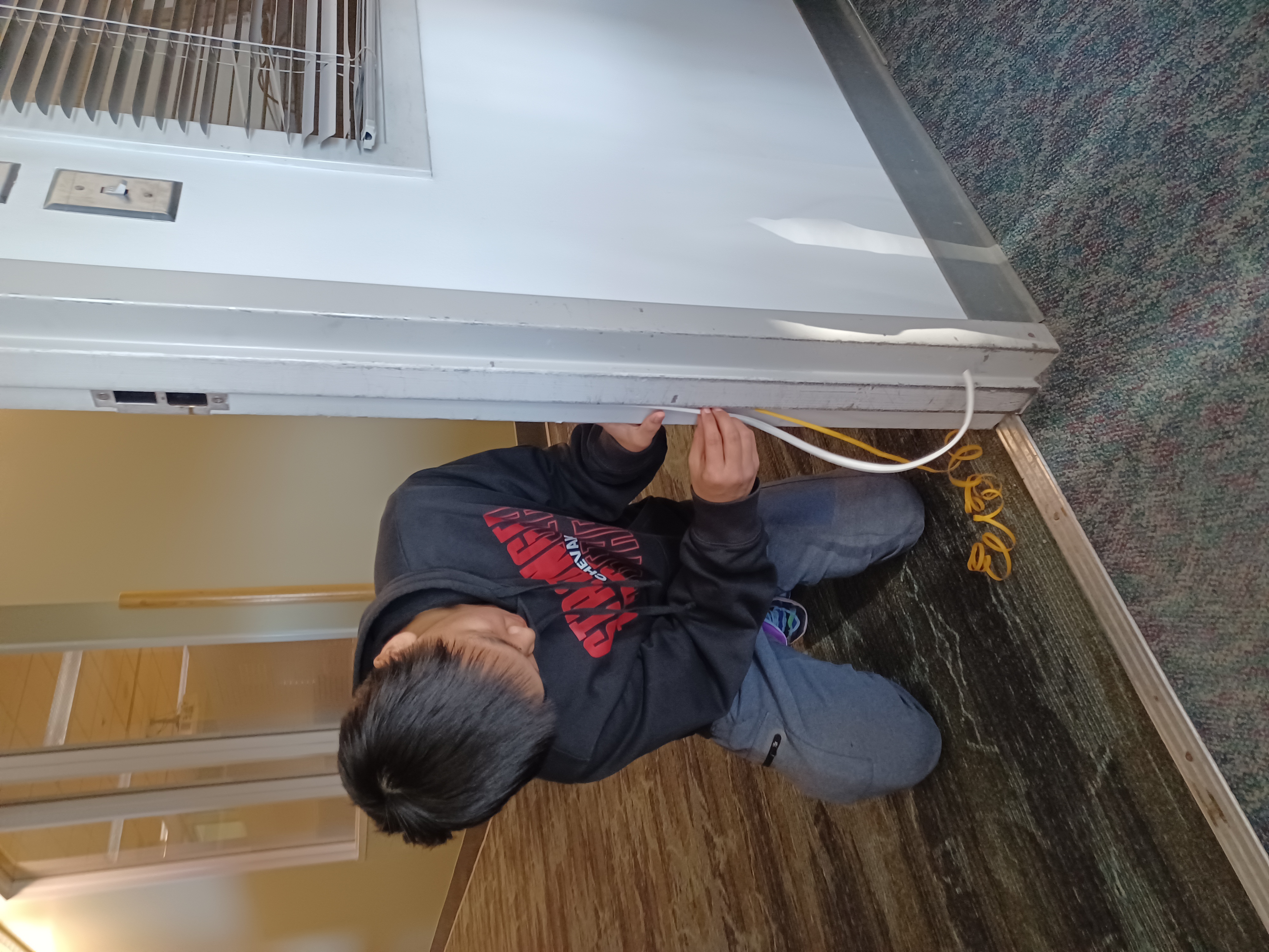 A T3 student learns to apply weather stripping to a classroom door frame. Photo by George Reising/ACEP. 