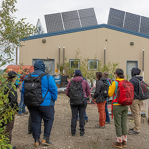 A group of energy leaders from the circumpolar Arctic look at solar panels installed on top of a maintenance building in Shungnak, Alaska. Photo by Amanda Byrd/ACEP.