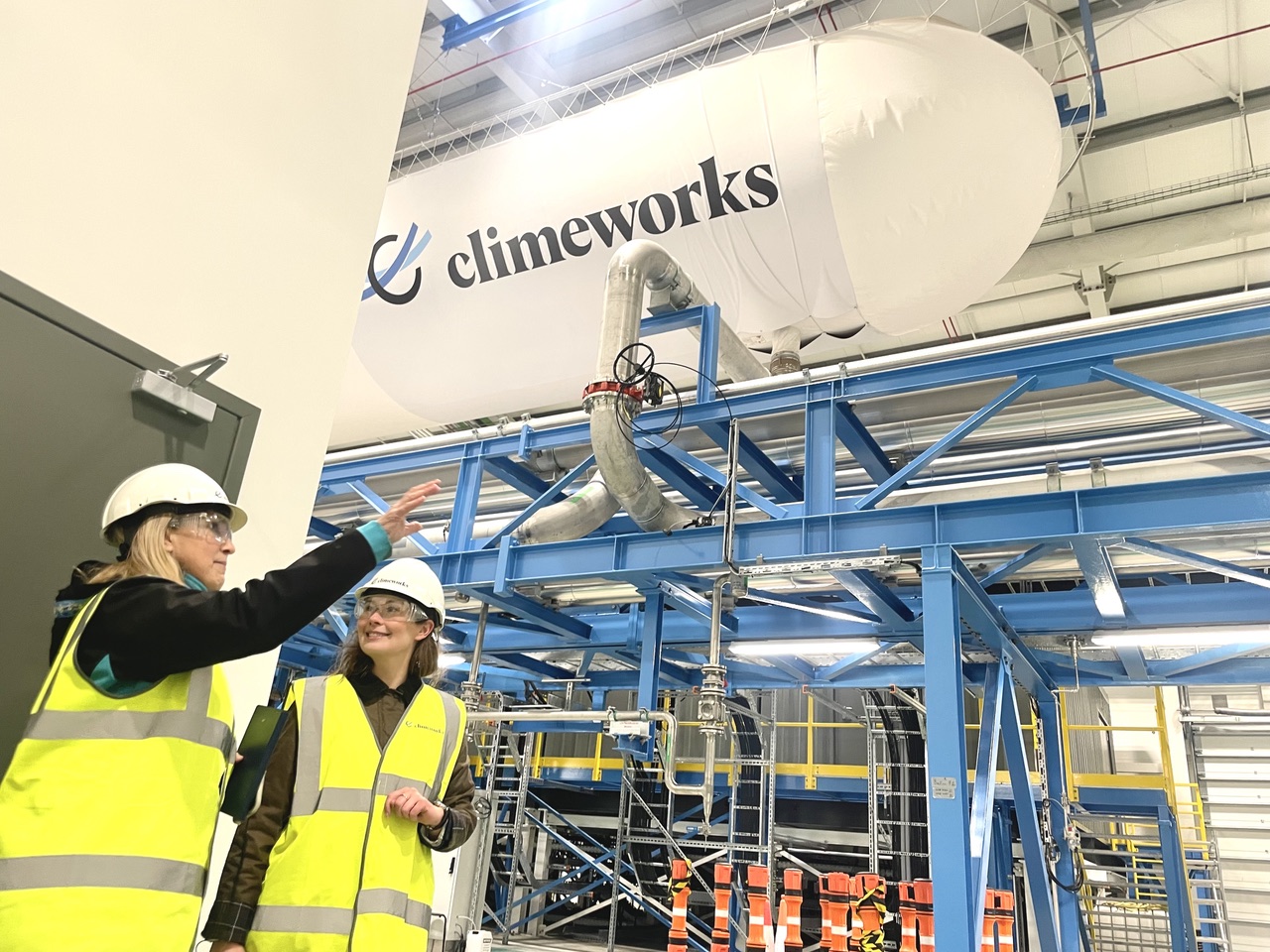 Two people in hard hats talking in a facility.
