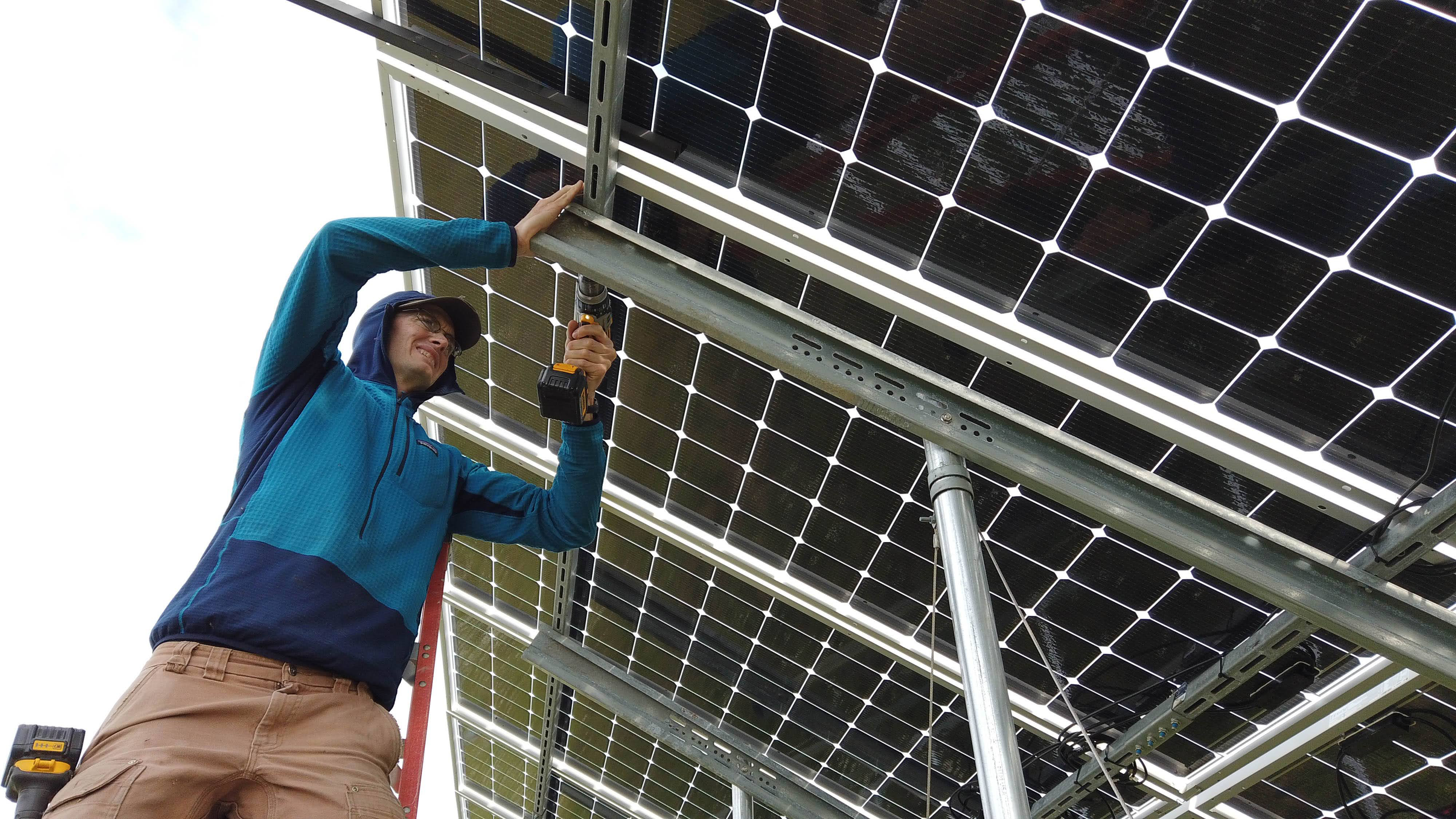 Chris Pike of ACEP installs a monitoring device on solar panels in Kotzebue, Alaska.