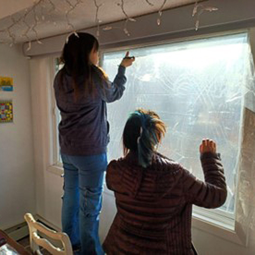 Students work together to retrofit a condo with window film. Photo by George Reising/ACEP