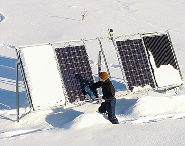 Person removing snow from solar panet