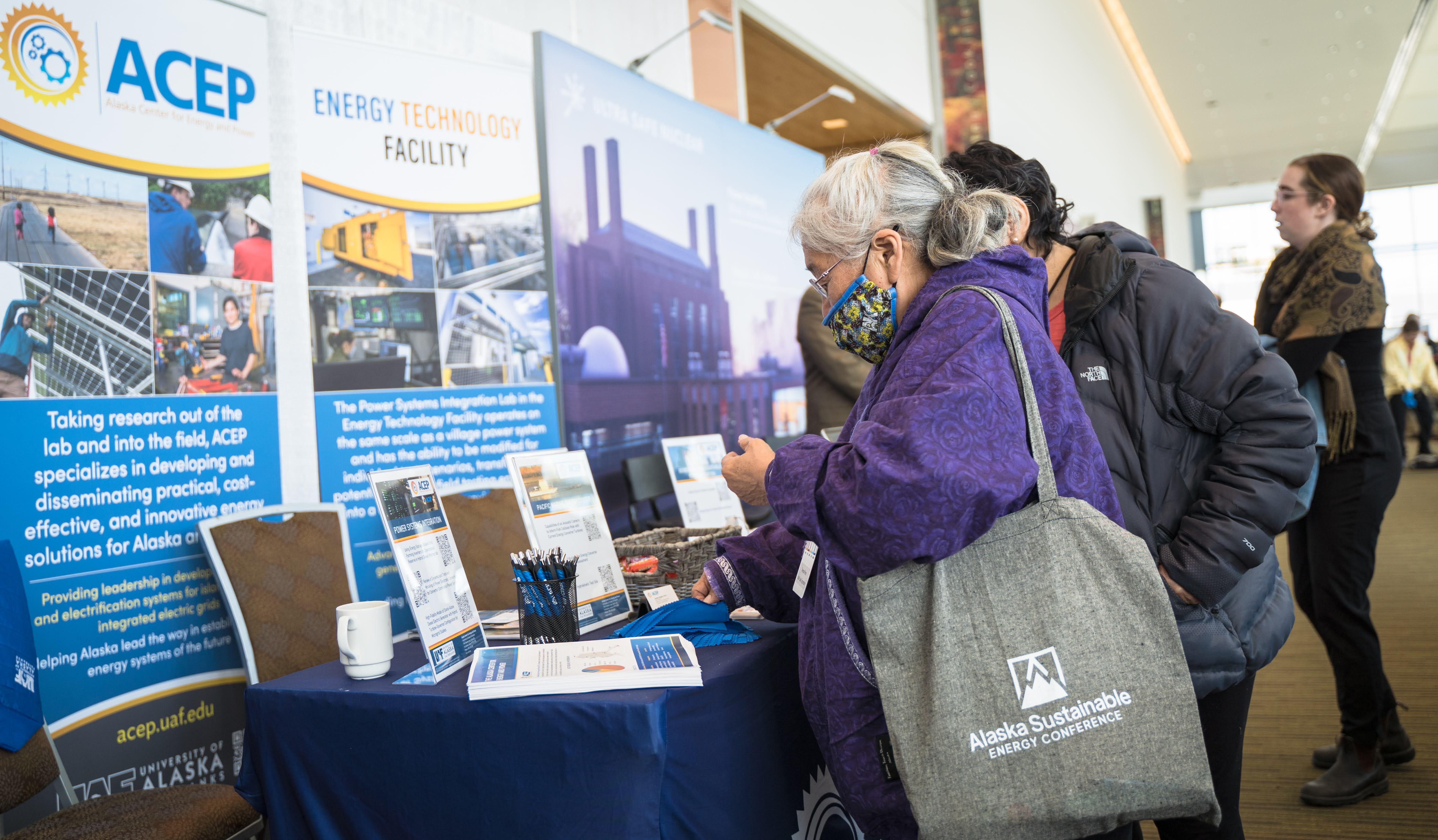 2022 Alaska Sustainable Energy Conference attendees visit ACEP's information table in between sessions. Photo by Jeff Fisher.