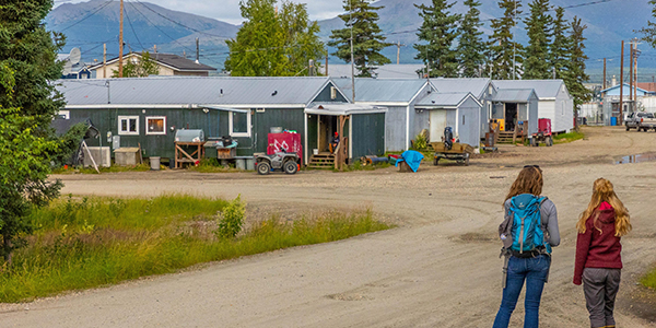 Two people standing on a road looking at houses in a rural community.