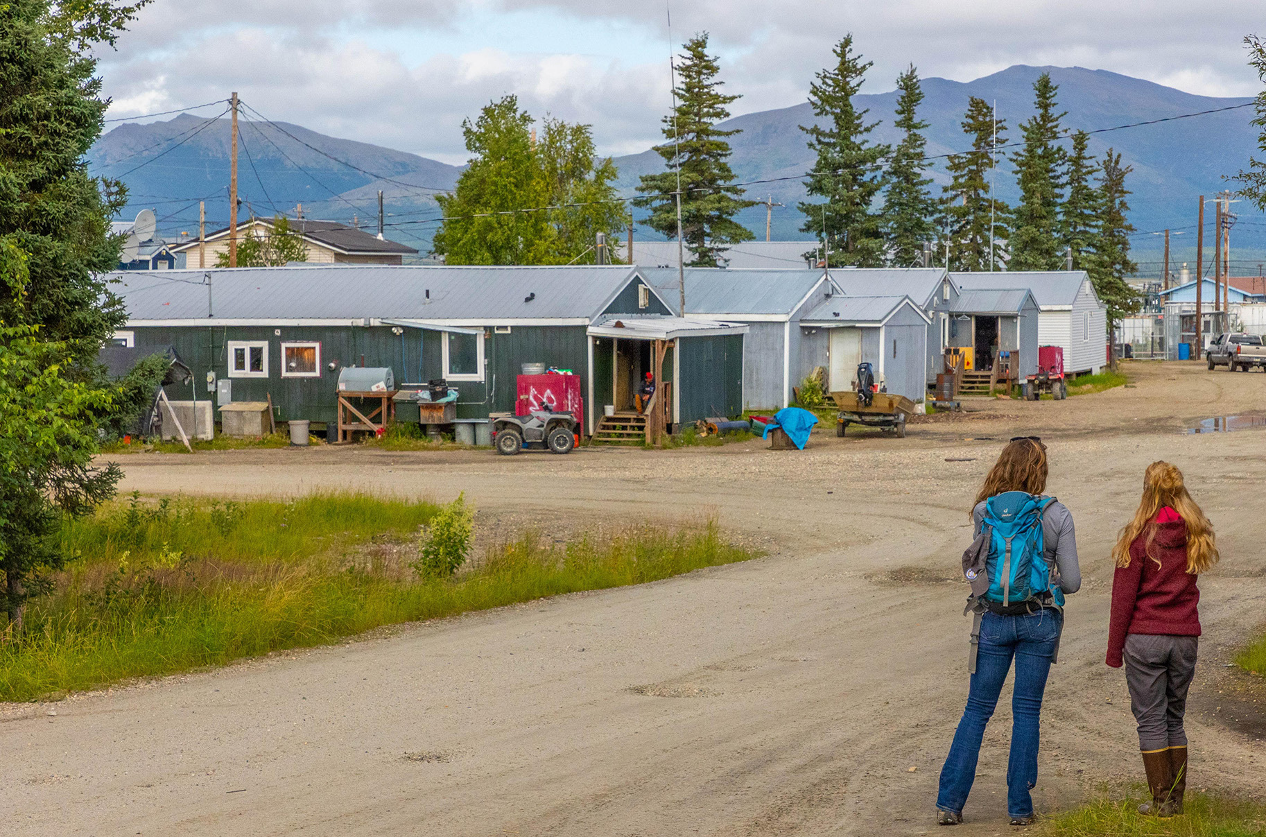 Two people standing on a road looking at houses in a rural community.