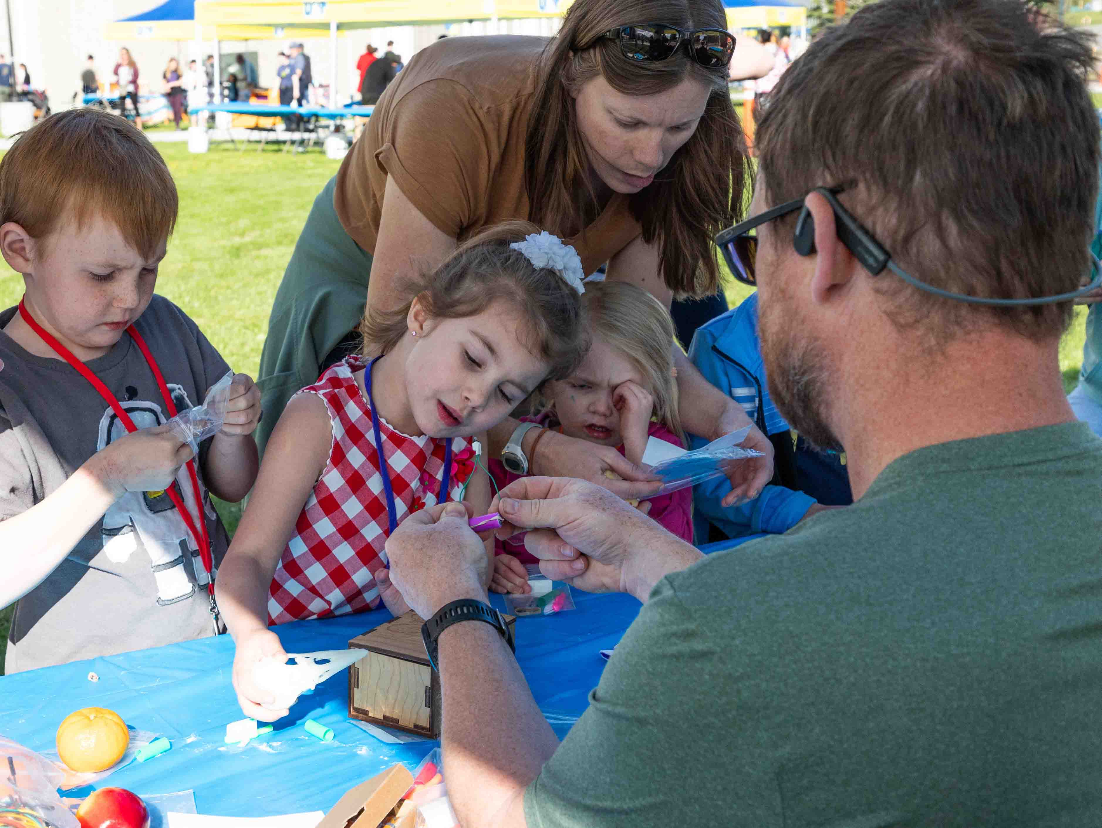 Children look on as Teaching Through Technology's Adam Low touches wires together that are attached to a battery, ready to power a robot toothbrush.
