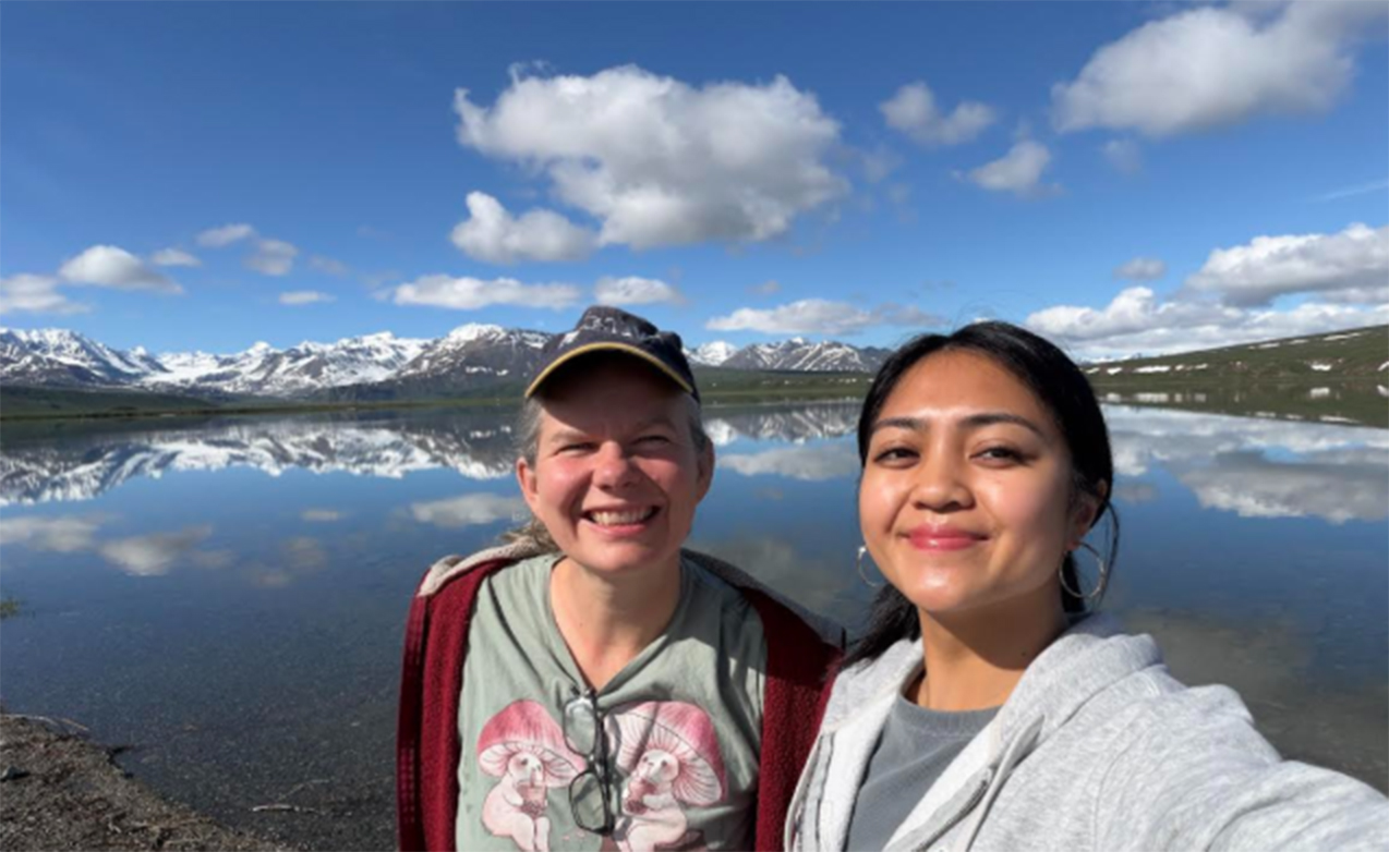 Two people taking a selfie with water and blue sky in the background