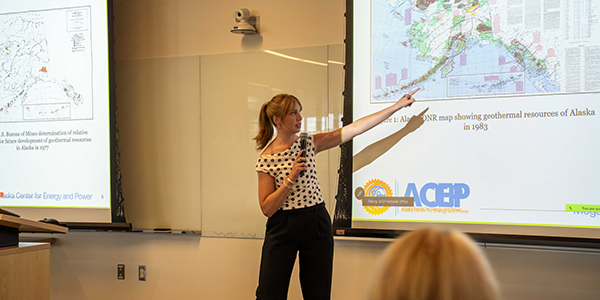A person is giving a presentation pointing at a screen.