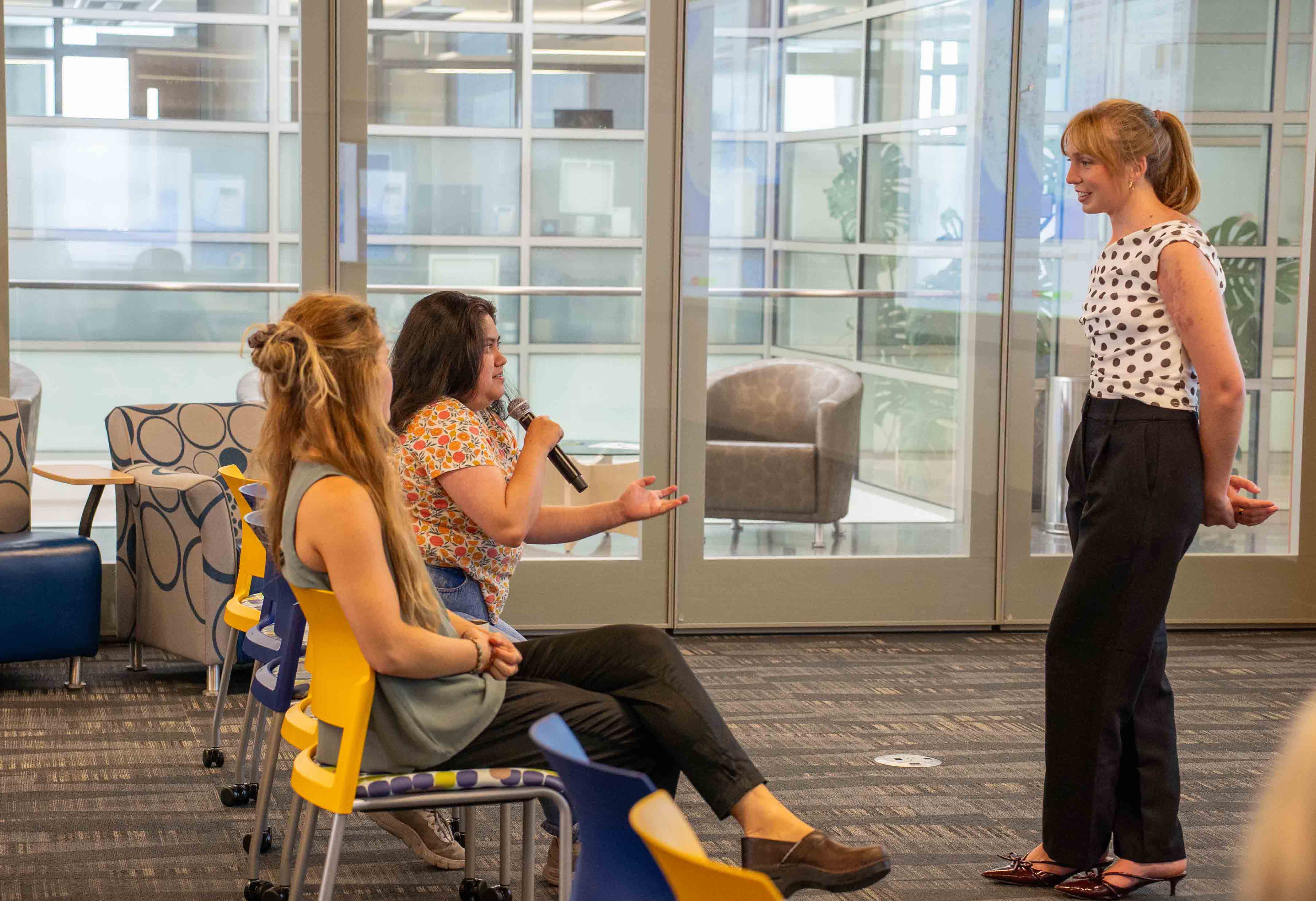A person with a mic asking a question while a person standing is listening
