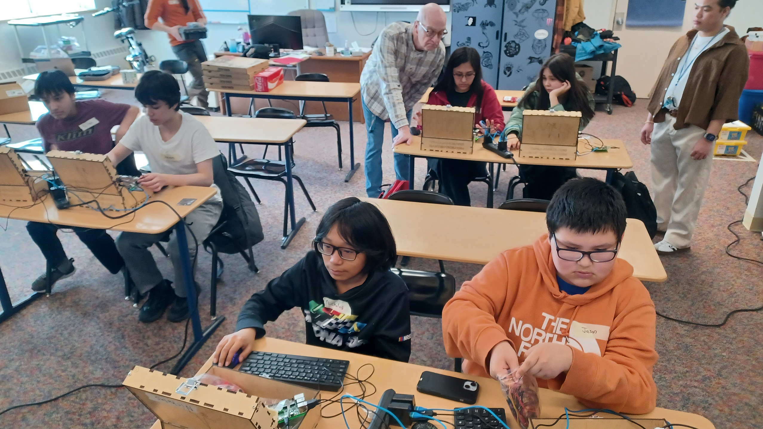 Teenagers work on small computers in a classroom