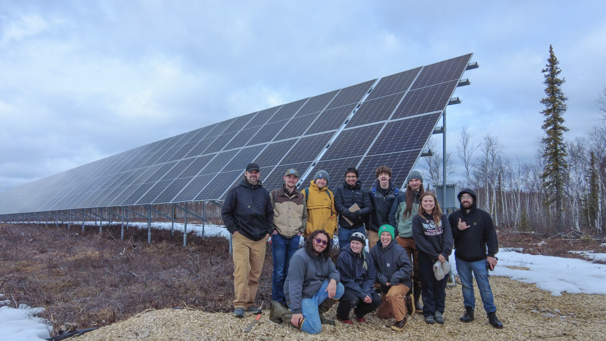 Eleven people stand in front of a solar array.