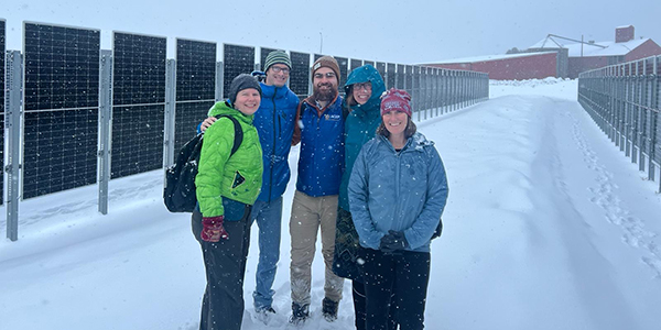 ACEP’s Michelle Wilber, Chris Pike, Henry Toal and Christie Haupert pose for a photo with Erin Whitney, the director of the U.S. Department of Energy Arctic Energy Office (second from right), at the vertical bifacial photovoltaic pilot plant installed by Sunna Group. Photo courtesy of Henry Toal/ACEP.