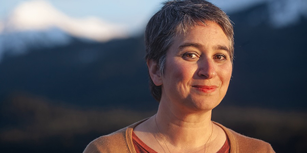 A person's headshot with a mountain in the background