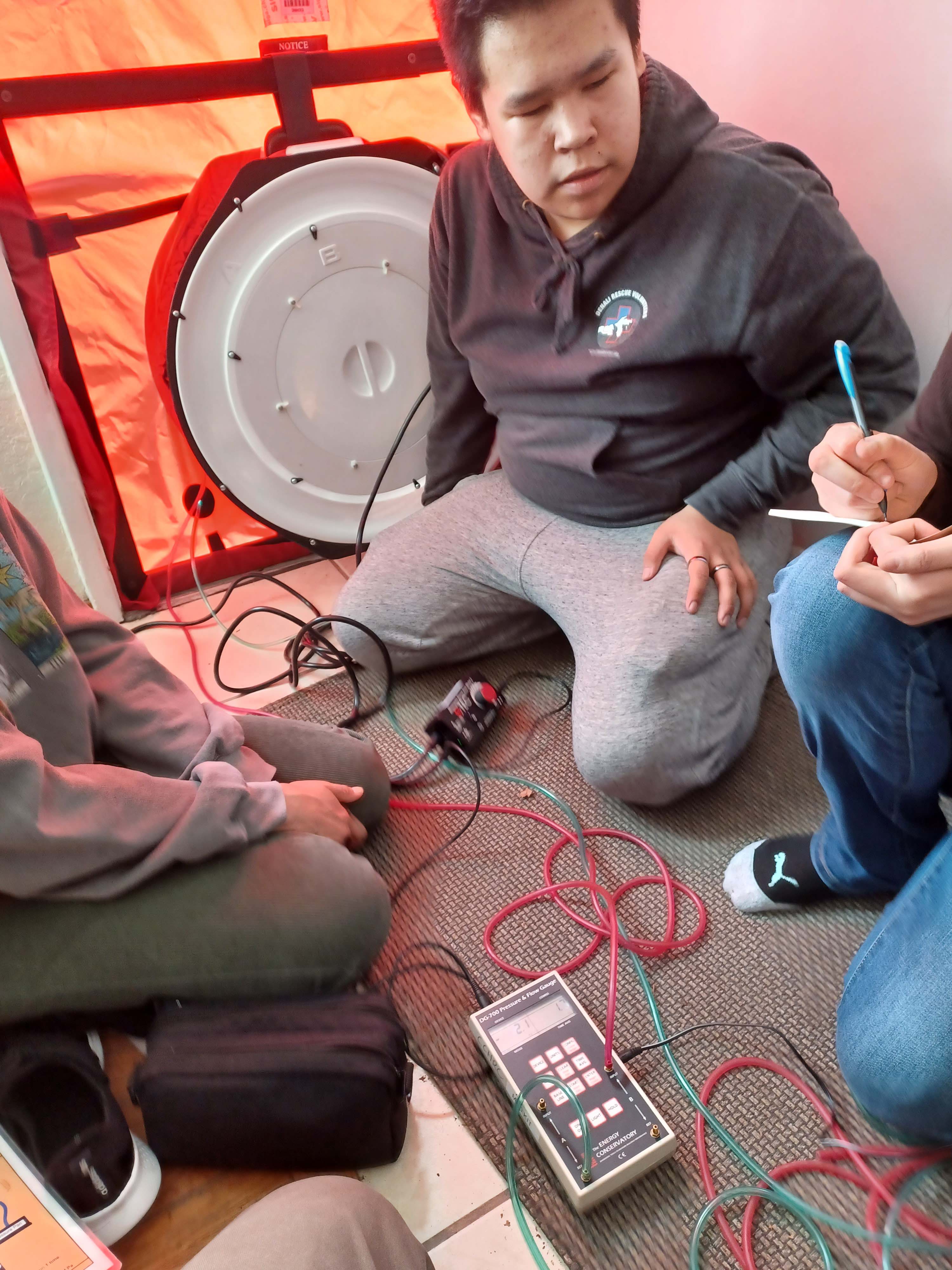 John Brink and students from Bethel record air exchange data from a blower-door test.