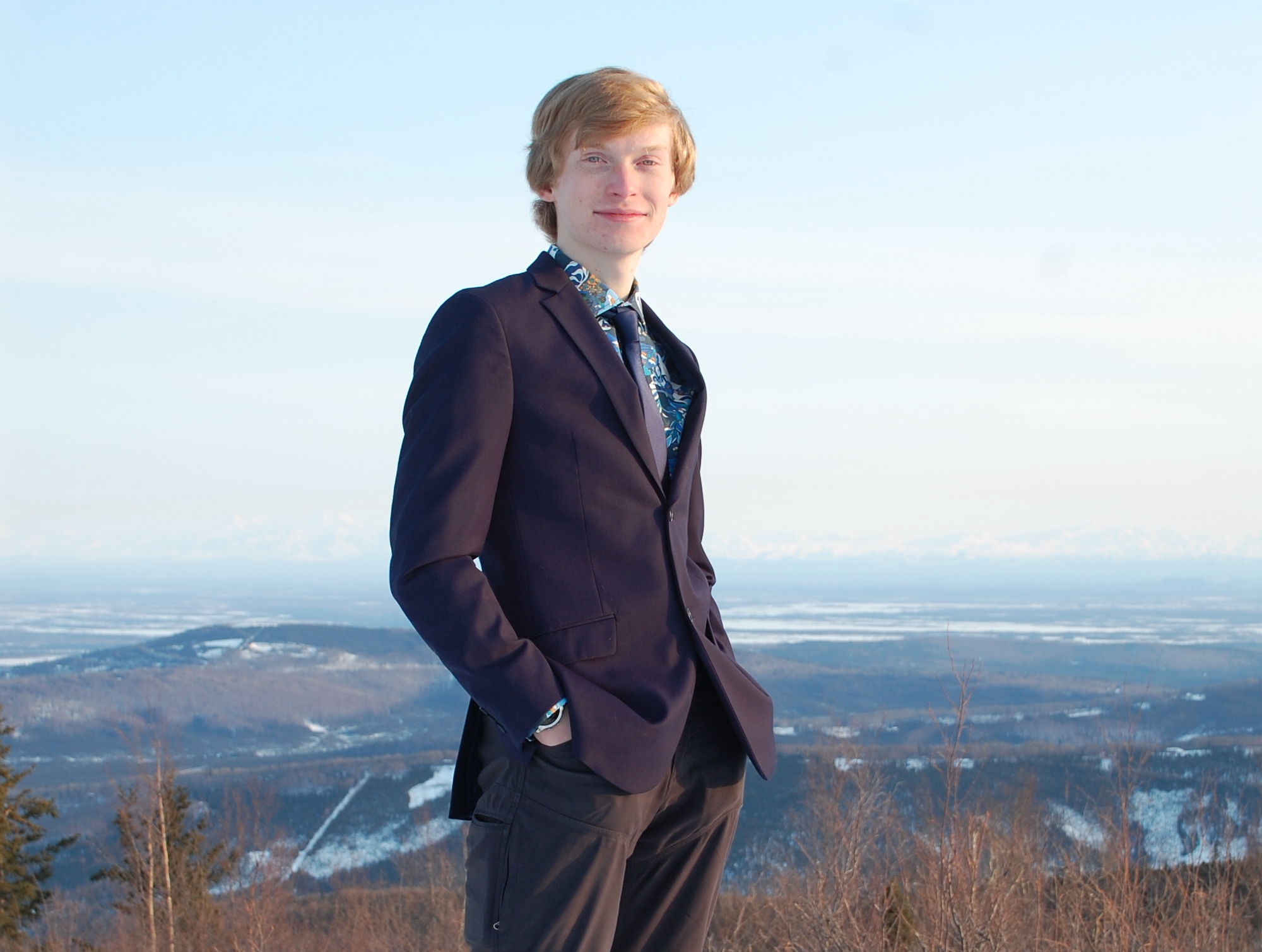 A person standing with hills and snowy mountains in the background