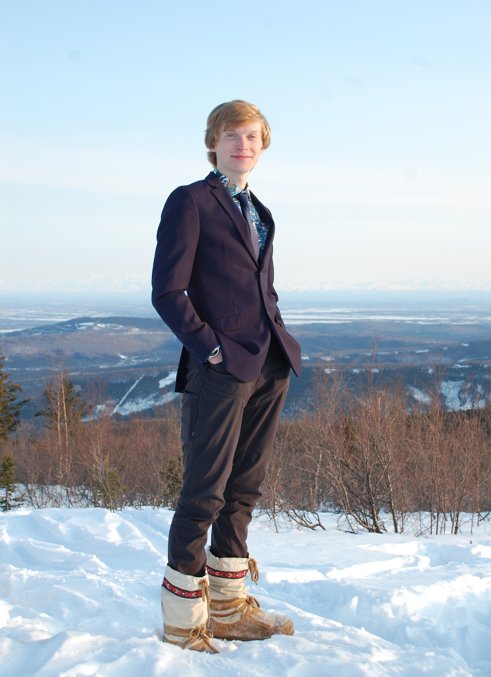A person standing on a snowy ground with hills in the background