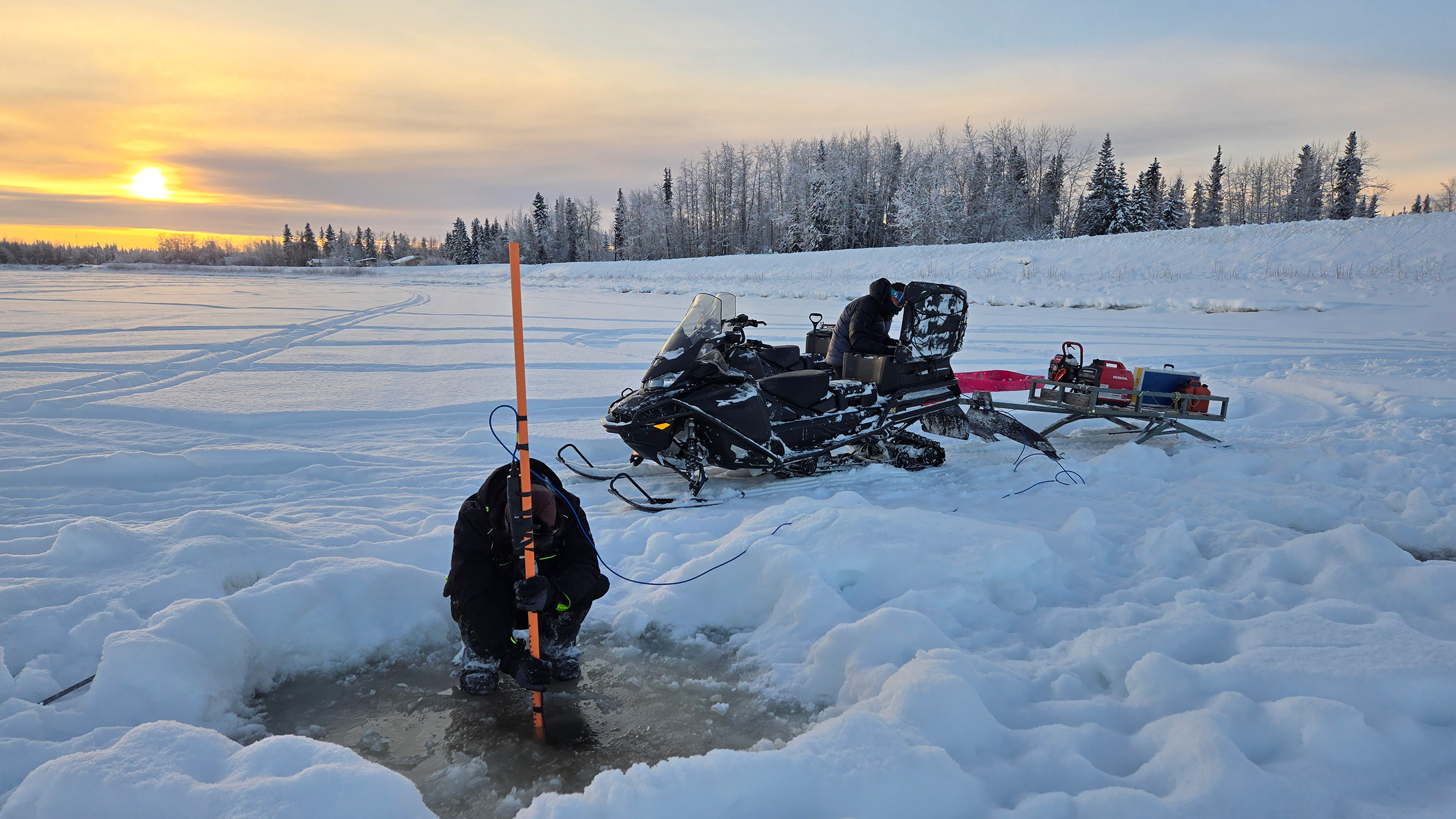 Two people doing fieldwork on a frozen river