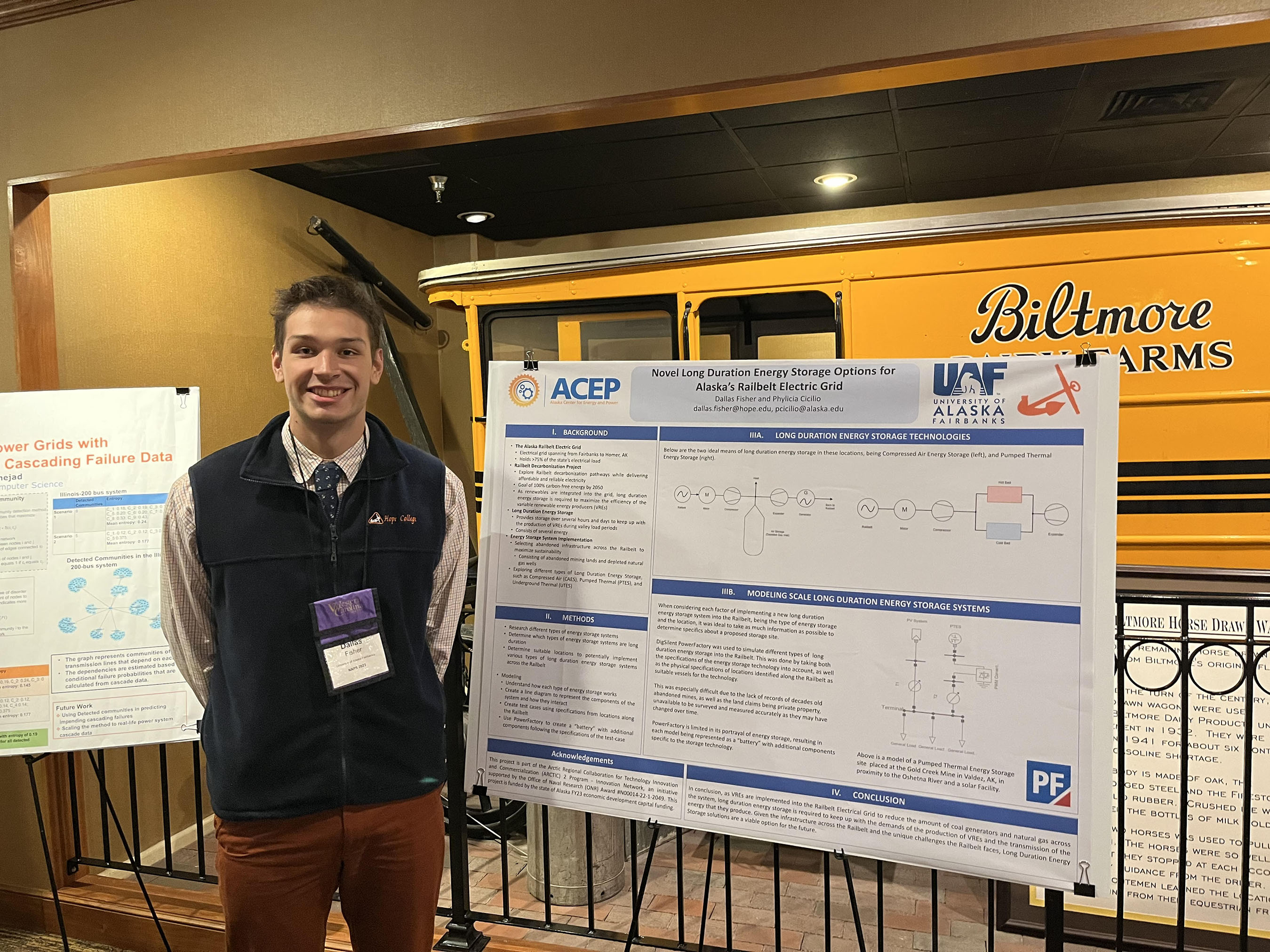 Dallas Fisher poses for a photo with his poster at the North American Power Symposium
