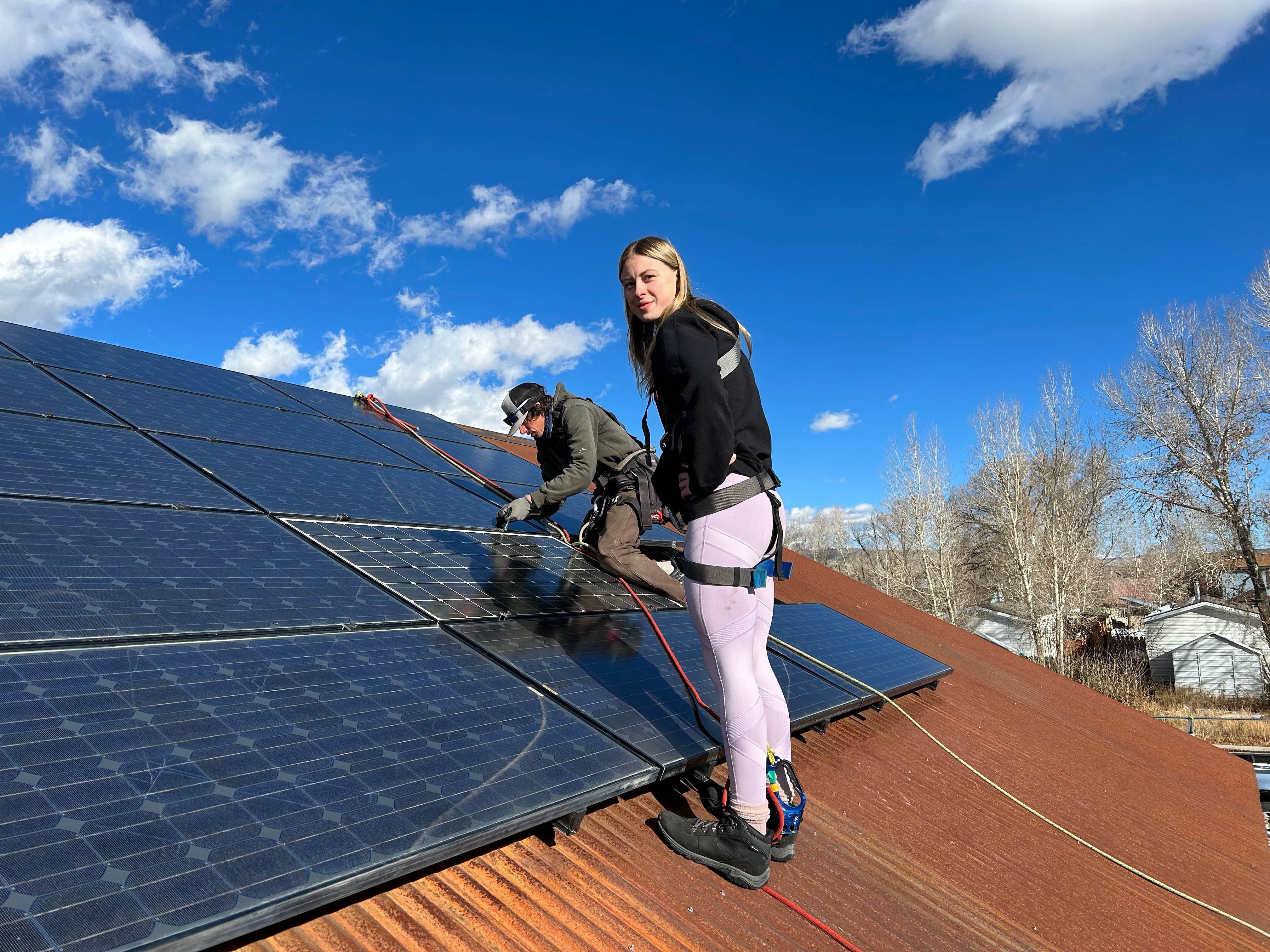 A student works with Nunatak Alternative Energy Solutions staff on a Habitat for Humanity house, using reused solar panels and rails.