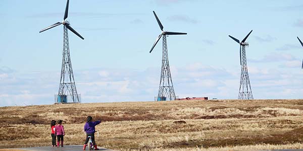 Children in Kongiganak on Alaska's Yukon-Kuskokwim Delta look out at wind turbines that provide power the remote community.