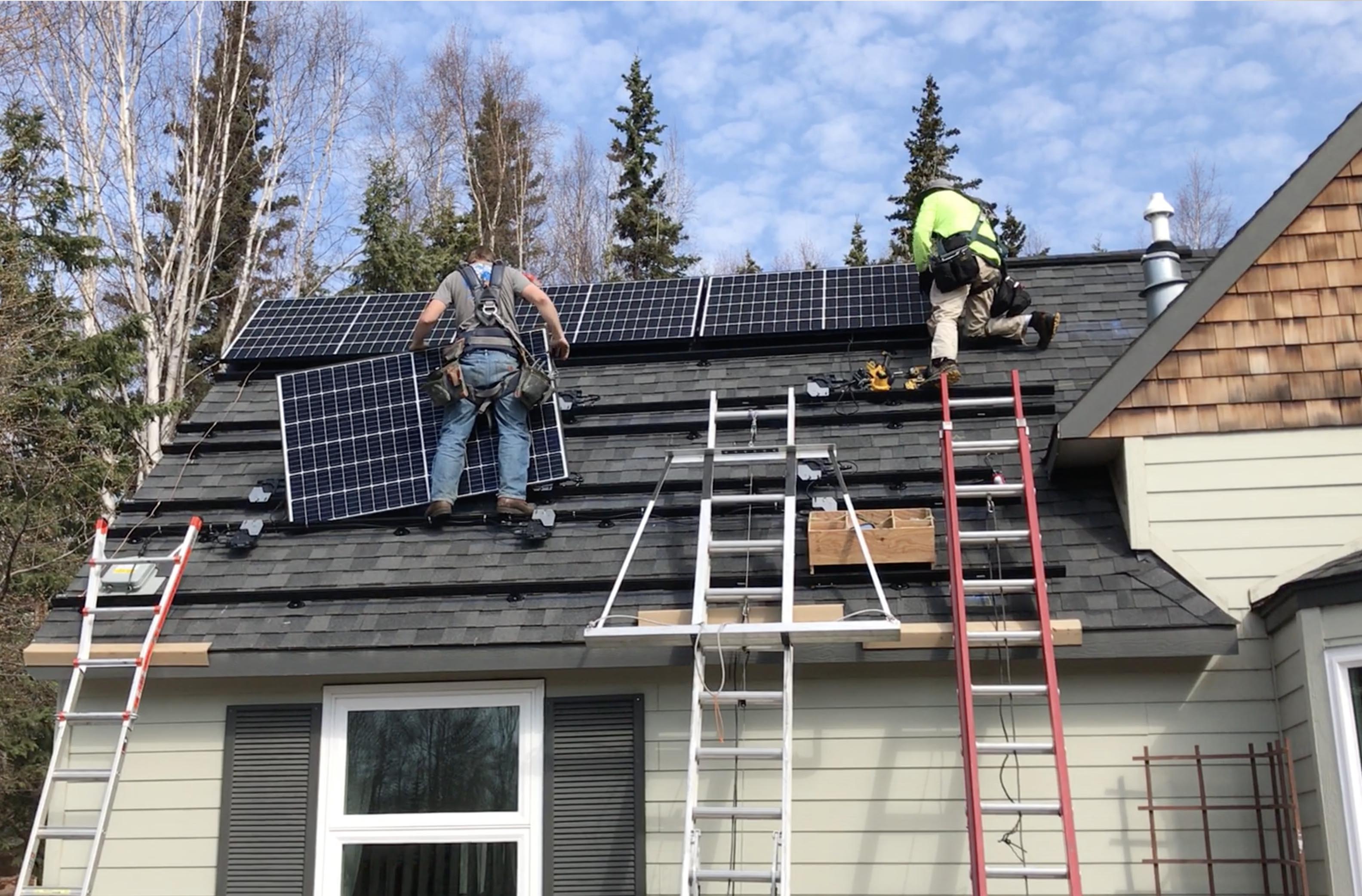 Solar panels being installed on a rooftop by workers