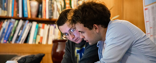 Two students talking over a book.