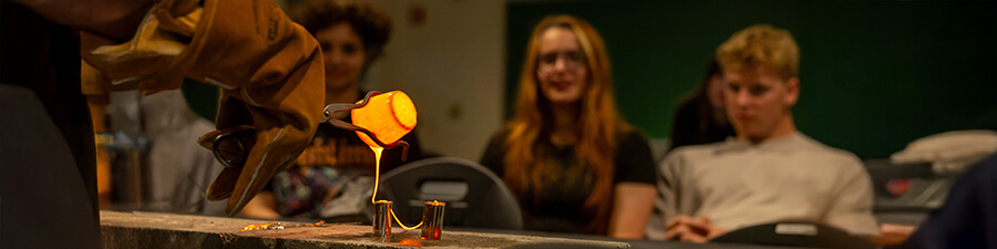 Students watching obsidian being poured during a campus tour.