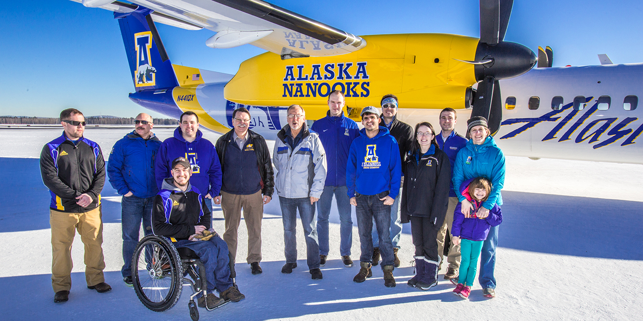Coaches, athletic department staff members and UAF administrators pose by one of the newest planes in the Alaska Airlines fleet, a Bombardier Q400 turboprop, which features the Alaska Nanooks and UAF.