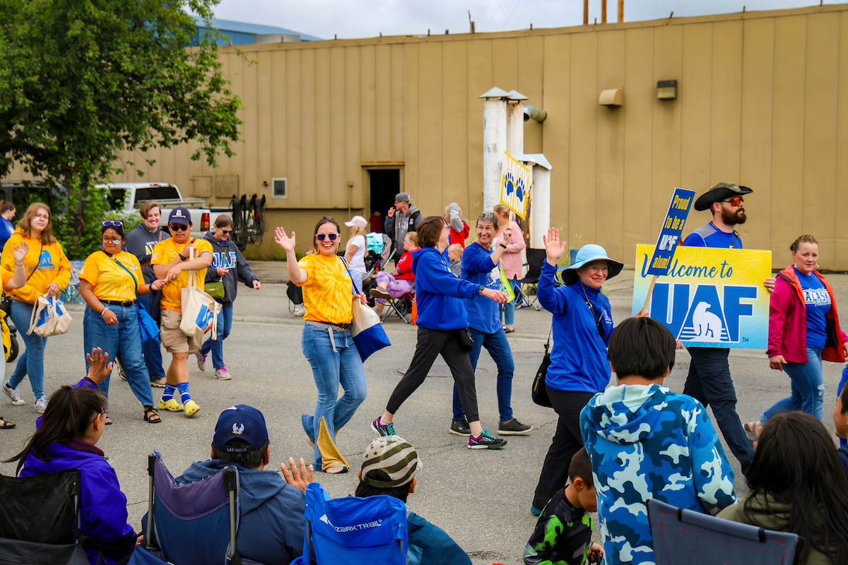 Alumni Storytelling Manager Katie Straub waves to the crowd while sporting a 70s throwback outfit as part of the theme for the 2023 Golden Days Parade.
