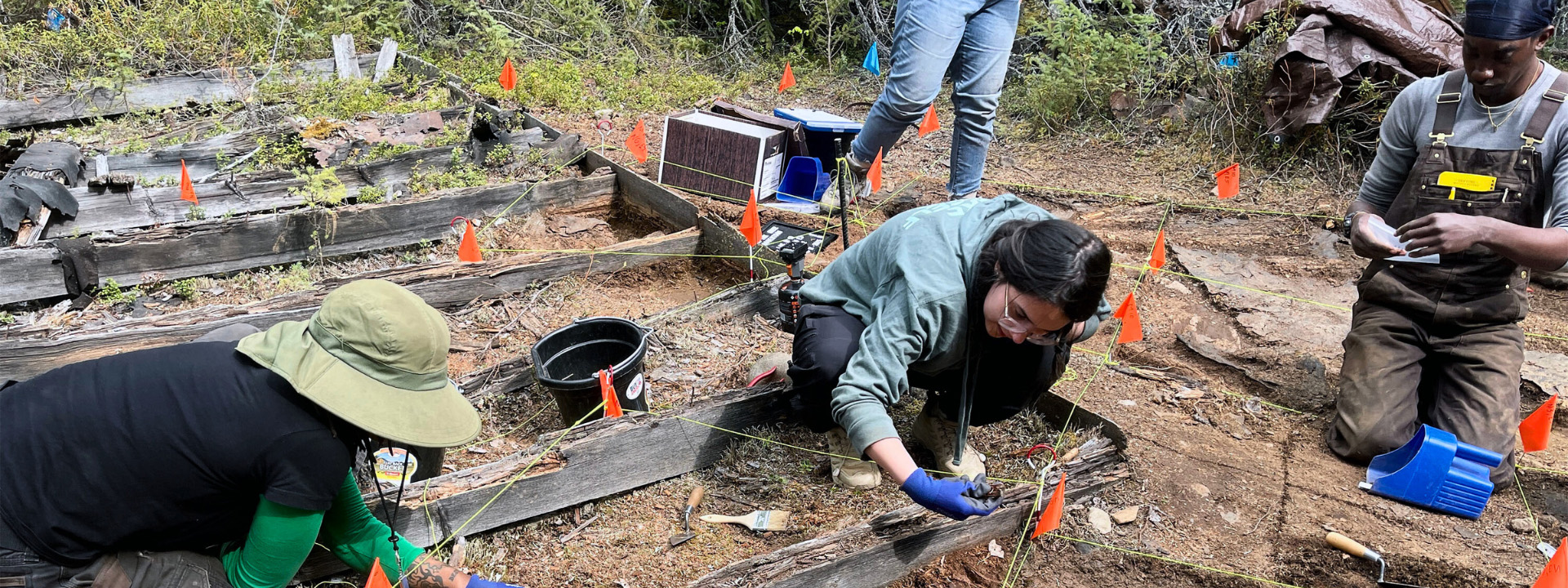 Alaska Highway Archaeological Field School students (Left to right T. Watson-Glen; Amilia Galdiano; Sean Adams) excavating the southeast corner of an outhouse. Photo courtesy of MoHagani Magnetek, June 2025.
