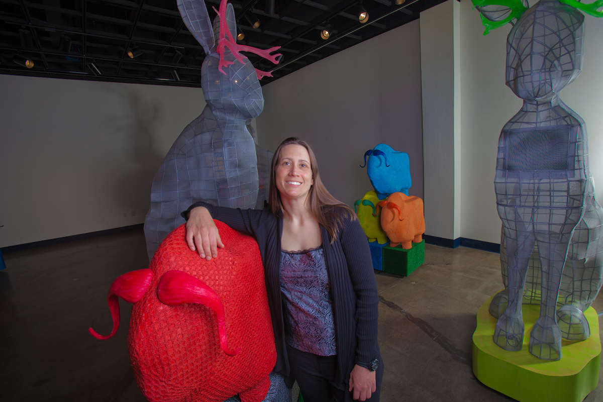 Lacie Stiewing poses with a few of her creations during her master of fine arts exhibition, "Fabulaskana," in the UAF art gallery. | UAF Photo by Todd Paris
