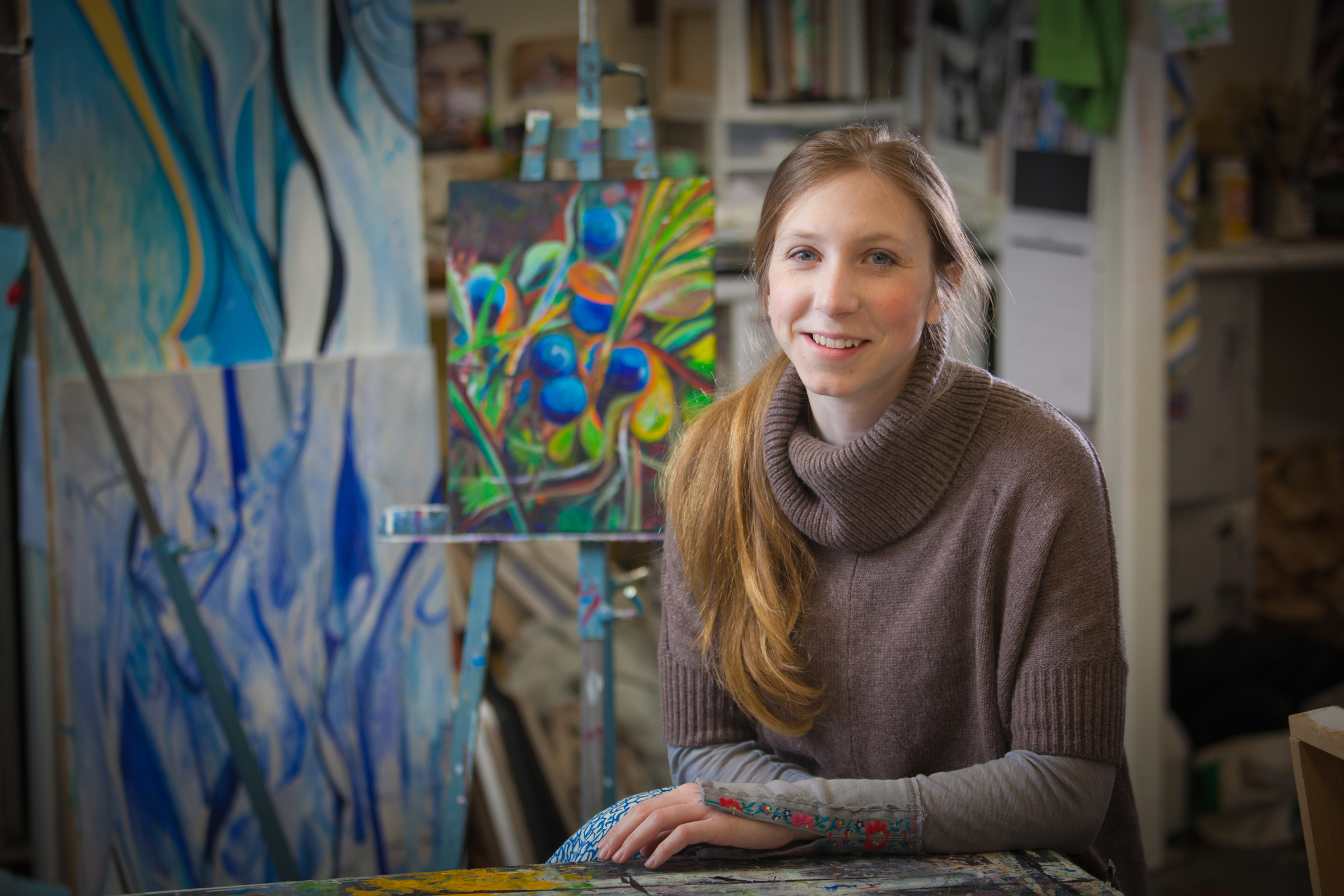 Art major Klara Maisch poses in front of one of her paintings in the Fine Arts studio. | UAF Photo by Todd Paris