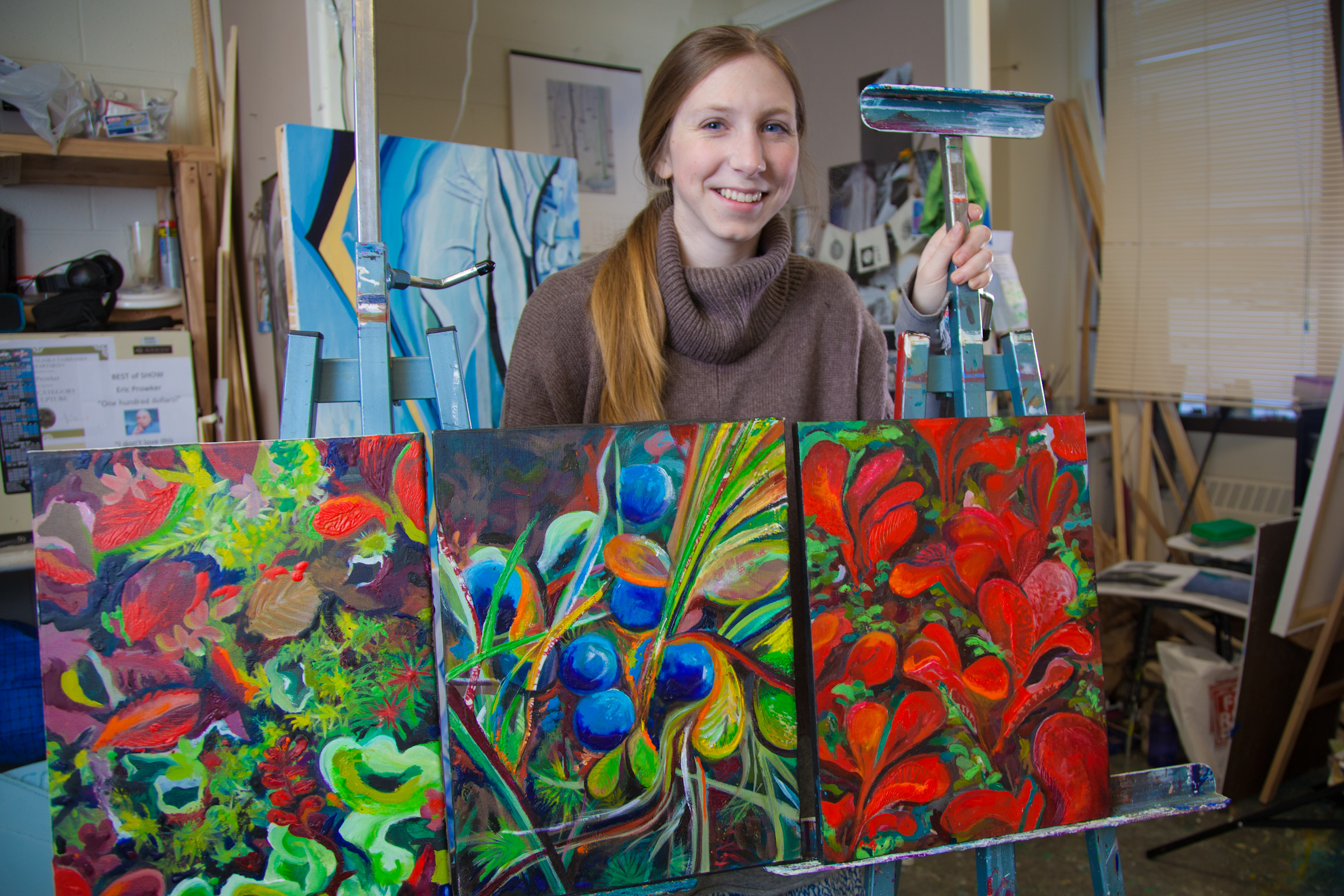 Art major Klara Maisch poses with some of her paintings in the Fine Arts studio. | UAF Photo by Todd Paris